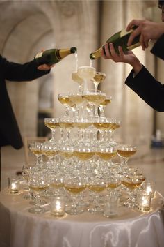 two people pouring champagne into wine glasses on top of a table