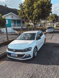 a white car is parked on the side of the road in front of a house