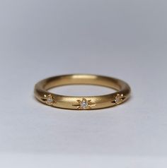 a yellow gold ring with three diamonds on the outside and in the middle, sitting on a white surface