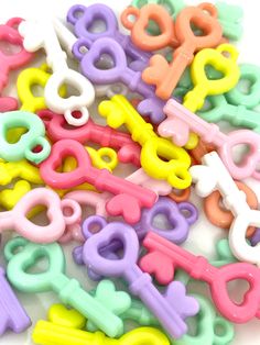 a pile of colorful plastic scissors on a white surface with clippings in the shape of letters