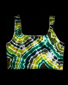 a green, yellow and white tie dye crop top on a black background in the dark