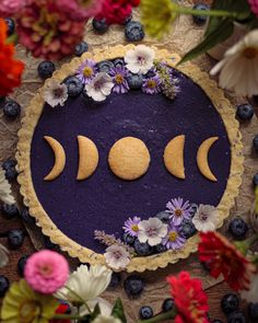 a cake decorated with flowers and three moon slices on top of purple frosted pie