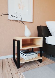 a wooden table with books on it in front of a bed and a painting hanging on the wall