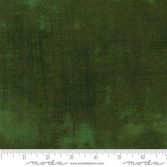 a ruler is next to a dark green background that looks like it has been dyed