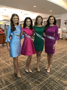 three beautiful young women standing next to each other in front of a carpeted floor