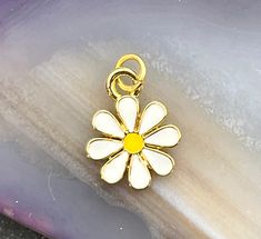 Enamel daisy charm.  18 kt. gold plated over brass. Sold individually.  MEASUREMENTS:  Approx. 5/8 inch (19mm) including the bail MATERIALS:  18kt gold plated over brass, enamel QUANTITY:  One Please message me with any questions. Thank you for looking and have a great day! Dainty Gold Flower Charm, Gold Flower Charm For Gift, Dainty Flower-shaped Enamel Jewelry, Dainty Yellow Flower Shaped Jewelry, Gold Flower Pendant Charms For Gifts, Gold Flower Pendant Charms As Gift, Yellow Gold Flower-shaped Jewelry With Charms, Gold Flower-shaped Enamel Jewelry, Gold Enamel Flower Jewelry