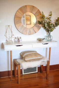 a white table with a mirror and some flowers on it