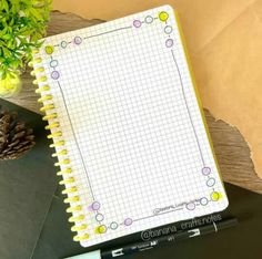 a notepad sitting on top of a desk next to a pen and flower pot