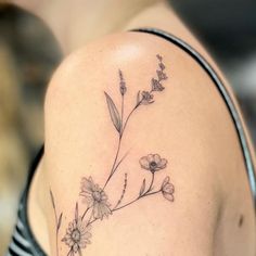 a woman's shoulder with flowers and leaves tattoo on her left side ribcage