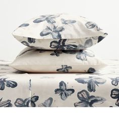 two pillows are stacked on top of each other with butterflies in blue and white colors