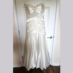 a white wedding dress hanging on a door