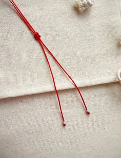 a red string is attached to a white piece of cloth