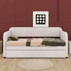 a white day bed sitting on top of a hard wood floor next to a red wall