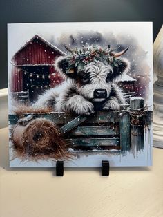 a painting of a cow with a wreath on its head sitting in front of a barn