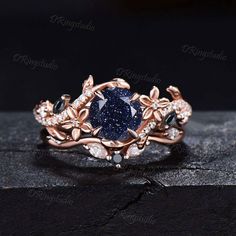 a blue diamond ring with leaves on the sides and diamonds around it, set in 18k rose gold