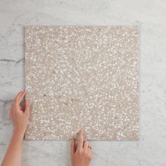 two hands on a marble board with white speckles