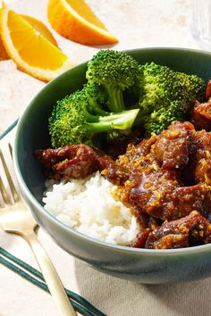 a bowl filled with rice, meat and broccoli on top of a table