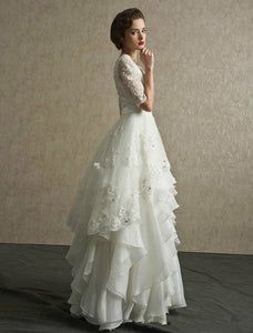 a woman in a white wedding dress standing with her hand on her chin