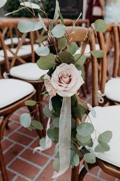 a bouquet of flowers sitting on top of a wooden chair next to some white chairs