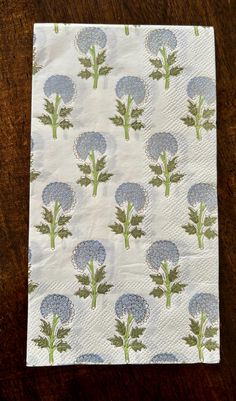 a napkin with blue flowers on it sitting on top of a wooden table next to a knife