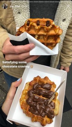 two waffles with chocolate on top are being held by someone