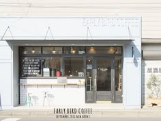 an empty coffee shop on the corner of a street in front of a white building