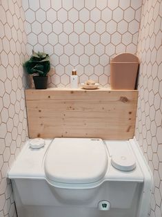 a white toilet sitting inside of a bathroom next to a wooden box on top of it