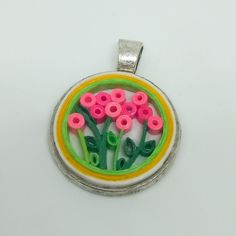 there is a pendant with pink flowers in the center and green stems on it's side