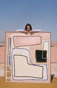 a woman sitting on top of a large piece of artwork in the middle of a desert