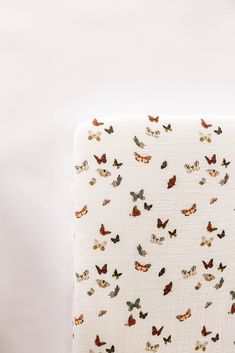 an upholstered bed with butterflies on it's back and white sheeting