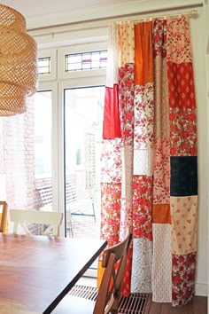 a dining room table and chairs in front of a window with colorful curtains hanging from it