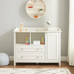 a baby's room with a white dresser and bookshelf