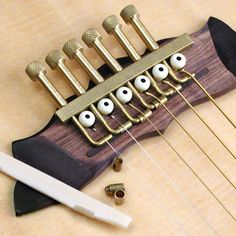 an acoustic guitar with five strings and six heads on top of it, next to a knife