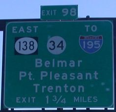 a green street sign with white lettering on it's side and an exit to belmar