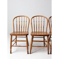 two wooden chairs sitting next to each other on a white surface with no one in it