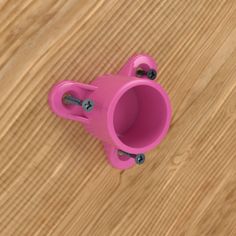 a pink plastic cup sitting on top of a wooden table with screws in it