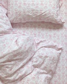 an unmade bed with pink and white comforter on top of it's sheets