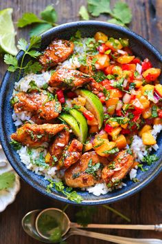 a blue bowl filled with rice, chicken and veggies next to cilantro