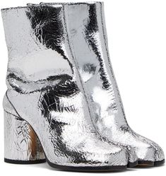 Find MAISON MARGIELA Silver Tabi Boots on Editorialist. Ankle-high cracked nappa leather boots in metallic silver tone. · Cleft toe · Hook-eye fastening at inner side · Signature white stitching at heel collar · Buffed lambskin lining · Covered cylindrical block heel with rubber injection · Leather sole · Heel: H3 Supplier color: Silver Metallic High Heel Leather Boots, Silver Leather Heeled Boots For Fall, Metallic Leather Heeled Boots With Pointed Toe, Silver Leather Heeled Boots For Spring, Glamorous Silver Leather Boots, Silver Boots With Reinforced Heel For Winter, Silver Winter Boots With Reinforced Heel, Winter Silver Boots With Reinforced Heel, Metallic Silver Leather Boots With Round Toe