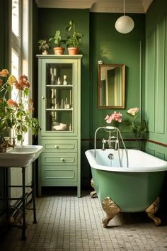 a green bathroom with a claw foot bathtub and flowers in the window sill