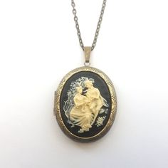 Classical style Victorian inspired large cameo locket necklace in black and cream. The detailed cameo has a black background, and is set on a large opening locket in gunmetal or antiqued bronze plated on a matching chain. The locket will hold two photos (approx the same size as the cameo), or any small precious object.  The locket measures just under 2 inches (50mm) from top to bottom, and the matching chain is has a lobster clasp. The chain length can be altered at no extra cost. Choose gunmeta Black Engraved Necklace For Wedding, Elegant Black Medallion Locket Necklace, Vintage Black Locket Necklace, Black Medallion Locket Necklace As A Gift, Black Medallion Locket Necklace, Vintage Black Cameo Necklace, Vintage Black Locket Necklace Gift, Antique Gold Cameo Medallion Locket Necklace, Vintage Collection Cameo Medallion Locket Necklace