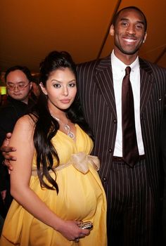 a man in a suit and tie standing next to a woman wearing a yellow dress