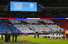 a group of people standing on top of a field next to each other in front of a large screen