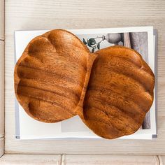 two wooden heart shaped dishes on top of a white plate with an image of a bird in the background