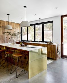 a kitchen with an island and bar stools in the middle, along with large windows