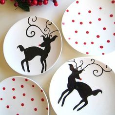 four plates decorated with black and red designs on them, one has a deer in its antlers