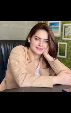 a woman sitting at a desk with her hand on her chin and looking off to the side