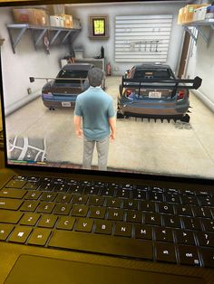 a man standing in front of a laptop computer with two cars on the screen next to him