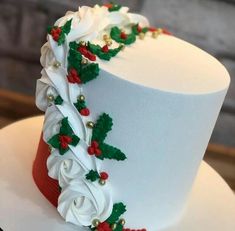 a white cake decorated with holly and red berries