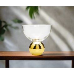 a yellow and white bowl sitting on top of a wooden table next to a plant